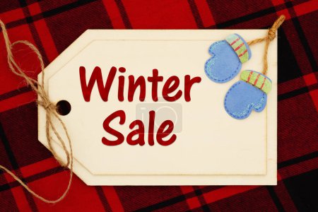 Téléchargez les photos : Message de vente d'hiver sur carte cadeau sur plaid de buffle rouge pour vos ventes de vacances - en image libre de droit
