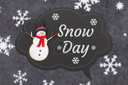 Téléchargez les photos : Message du jour de neige sur un panneau de craie à bulles avec un bonhomme de neige sur du tissu de flocon de neige - en image libre de droit