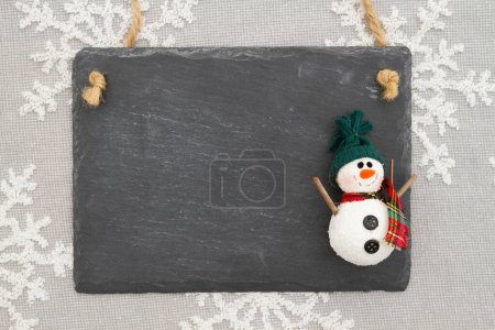 Téléchargez les photos : Panneau de tableau blanc avec un bonhomme de neige sur flocons de neige pour votre message d'hiver ou saisonnier - en image libre de droit