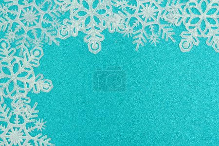 Photo for White snowflakes on teal glitter winter season background for your winter or seasonal message - Royalty Free Image