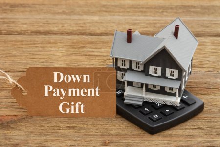 Foto de Down Payment Gift rules with a mortgage calculator and gift tag with a house on a wood desk - Imagen libre de derechos