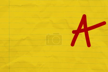 Téléchargez les photos : Getting a grade A message on bright yellow ruled line notebook crumpled paper - en image libre de droit