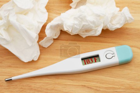Foto de Digital thermometer with a display for taking your temperature on a wood desk - Imagen libre de derechos