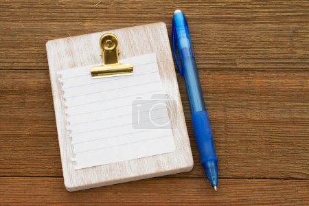 Téléchargez les photos : Blank lined paper on a chipboard with a pen on weather wood desk - en image libre de droit