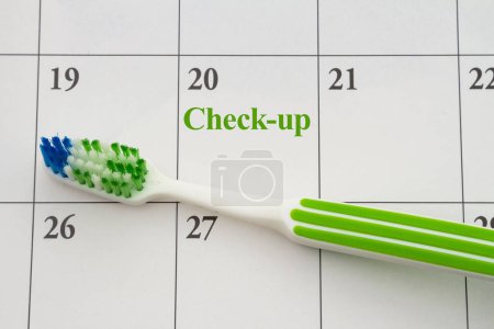 Photo for Toothbrush on a calendar for scheduling dentist appointment for your checkup - Royalty Free Image