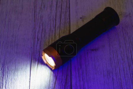 Foto de Black and bronze LED flashlight on wood table for your emergency ready kit - Imagen libre de derechos