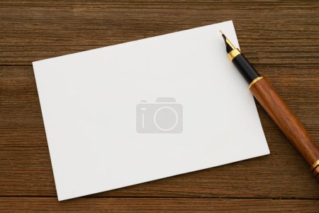 Photo for Blank greeting card with a fountain pen on weathered wood desk - Royalty Free Image