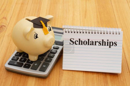 Foto de Scholarships message with gold piggy bank with a grad cap, notebook, and calculator on wood desk for your money or saving for school - Imagen libre de derechos