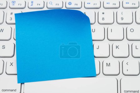 Téléchargez les photos : Blank blue sticky note on a profile gray computer keyboard for your online shopping message - en image libre de droit