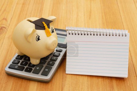 Foto de Gold piggy bank with a grad cap, notebook, and calculator on wood desk for your money or saving for school - Imagen libre de derechos