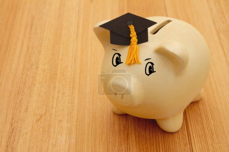 Photo for Gold piggy bank with a grad cap on wood desk for your money or saving for school - Royalty Free Image