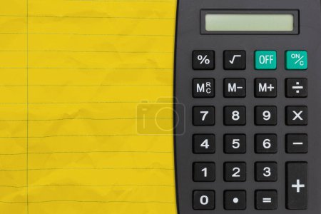 Photo for Bright yellow ruled line notebook crumpled paper with a calculator for you education or school message - Royalty Free Image