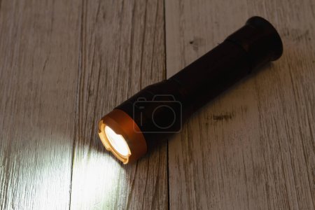 Photo for Black and bronze LED flashlight on wood table for your emergency ready kit - Royalty Free Image