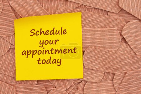 Foto de Schedule your appointment today on sticky note with lots of fabric adhesive band aids with for your doctor or test appointment message - Imagen libre de derechos