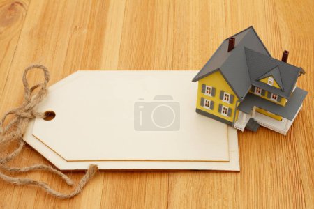 Foto de Blank gift tag with a house on a wood desk for you mortgage message - Imagen libre de derechos