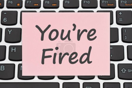 Photo for Youre Fired on a pink slip on a computer keyboard letting someone know they have been laid off - Royalty Free Image