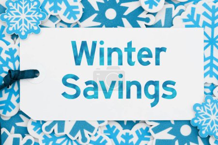 Téléchargez les photos : Winter Savings message on a gift tag with blue snowflakes for winter sales message - en image libre de droit