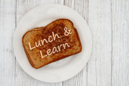 Lunch and Learn message on a plate with a sandwich on wood table