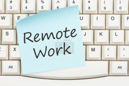 Téléchargez les photos : Message de travail à distance sur une note collante bleue sur un clavier d'ordinateur gris pour votre message de travail à la maison - en image libre de droit