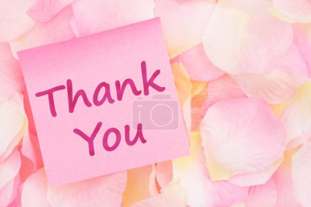 Foto de Mensaje de agradecimiento en una nota adhesiva rosa con pétalos de rosa rosa y amarillo para su mensaje de San Valentín o aniversario - Imagen libre de derechos