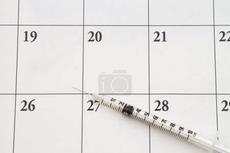 Téléchargez les photos : Seringue d'aiguille sur un calendrier pour prendre rendez-vous pour votre injection de vaccin - en image libre de droit