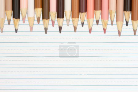 Foto de Fondo de lápices de color de tono de piel multicultural en papel forrado para usted educación o mensaje escolar - Imagen libre de derechos