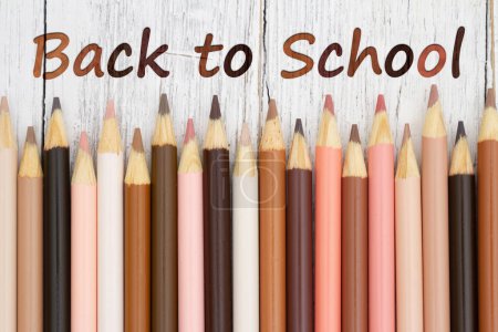 Téléchargez les photos : Message de retour à l'école avec des crayons de couleur multiculturels sur un bureau en bois altéré - en image libre de droit