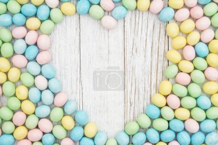 Foto de Fondo de huevo de Pascua de caramelo de color pastel con corazón en madera envejecida para su mensaje de vacaciones - Imagen libre de derechos