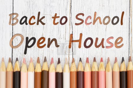 Téléchargez les photos : Message de retour à l'école pour les portes ouvertes avec des crayons de couleur multiculturels sur un bureau en bois altéré - en image libre de droit