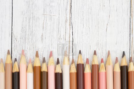 Téléchargez les photos : Crayons de couleur de peau multiculturels fond sur le bois météo pour vous message éducatif ou scolaire - en image libre de droit