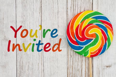 Photo for Youre Invited message with colorful swirl lollipop on weathered wood - Royalty Free Image