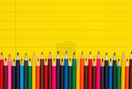 Photo for Color pencils crayons on vintage yellow ruled line notebook paper background for you education or school message - Royalty Free Image