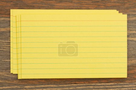 Foto de Pila de tarjetas de índice de papel amarillo retro en escritorio de madera con espacio de copia para su mensaje - Imagen libre de derechos