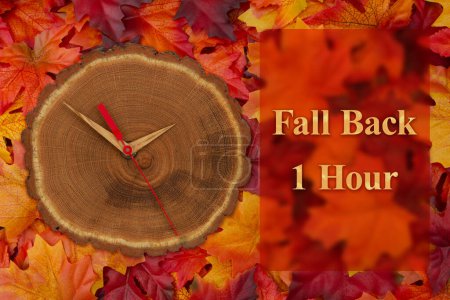 Foto de Cambio de hora de 1 hora con reloj de madera en hojas de otoño - Imagen libre de derechos