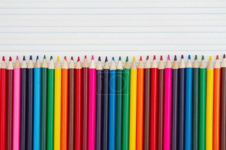 Foto de Lápices de colores lápices de colores sobre fondo de papel de cuaderno de línea reglada vintage para usted educación o mensaje escolar - Imagen libre de derechos