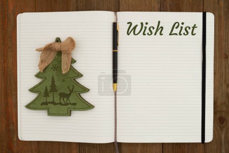 Photo for Wish List with a pen and Christmas tree on ruled line journal paper page notepad on weathered desk - Royalty Free Image