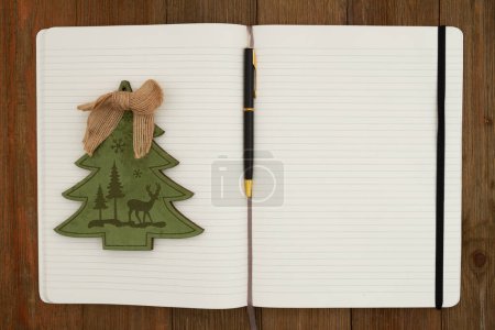 Photo for Ruled line journal paper page notepad Christmas tree and pen background on weathered desk for writing or journaling - Royalty Free Image