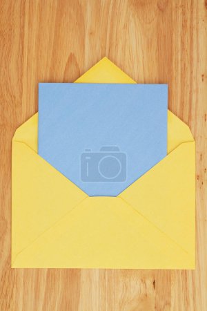 Téléchargez les photos : Carte de vœux vierge avec enveloppe jaune sur bureau en bois - en image libre de droit