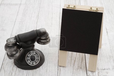 Photo for Vintage retro rotary dial phone with chalkboard on a weathered wood table - Royalty Free Image