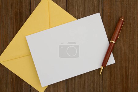 Photo for Blank greeting card with yellow envelope and pen on weathered wood - Royalty Free Image