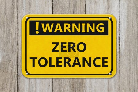 Warning Zero Tolerance yellow sign on a weathered wood wall
