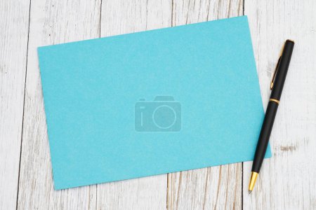 Foto de Tarjeta de felicitación azul en blanco y bolígrafo en madera envejecida - Imagen libre de derechos