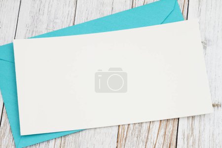 Foto de Tarjeta de felicitación en blanco con sobre azul sobre madera envejecida - Imagen libre de derechos
