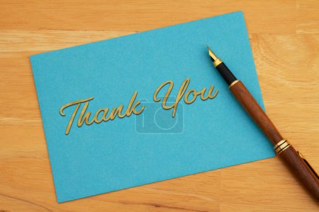 Foto de Gracias felicitación tarjeta azul y pluma en escritorio de madera - Imagen libre de derechos