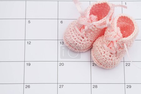 Photo for Pink baby booties on a calendar with space for you message - Royalty Free Image