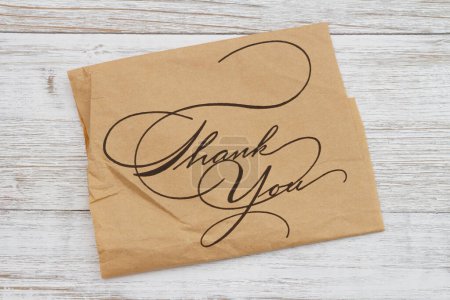 Photo for Thank you note on brown crumpled butcher paper on weathered wood - Royalty Free Image