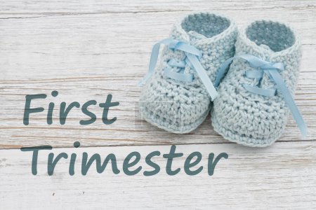 Photo for First Trimester message with blue baby booties on weathered wood - Royalty Free Image