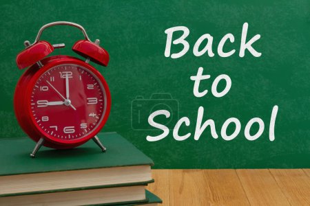 Téléchargez les photos : Message de retour à l'école avec réveil sonnette rouge sur les livres avec tableau - en image libre de droit