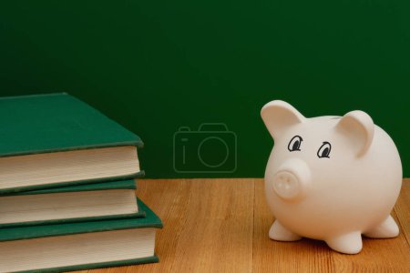 Foto de Ahorro de dinero para la educación con alcancía, libros, escritorio y pizarra - Imagen libre de derechos