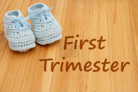 Photo for First Trimester message with blue baby booties on wood - Royalty Free Image